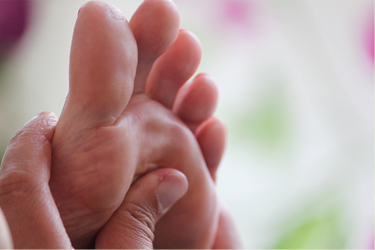 massage d'un zone spécifique du pied gauche pendant une séance de réfléxologie plantaire